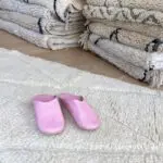 Marokkanske håndlavede slippers i rosa oven på beni ouarain tæppe
