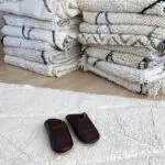 Marokkanske håndlavede slippers i mørkebrun ved siden af beni ouarain tæpper