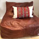 Håndvævet vintage kelim boho pudebetræk i rød og beige med marokkansk mønster med kvaster på kanterne på sækkestol
