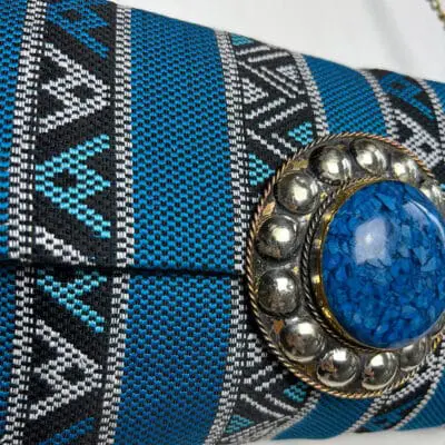 handtas van blauwe stof met patroon, ritssluiting aan de binnenkant en koperen ketting