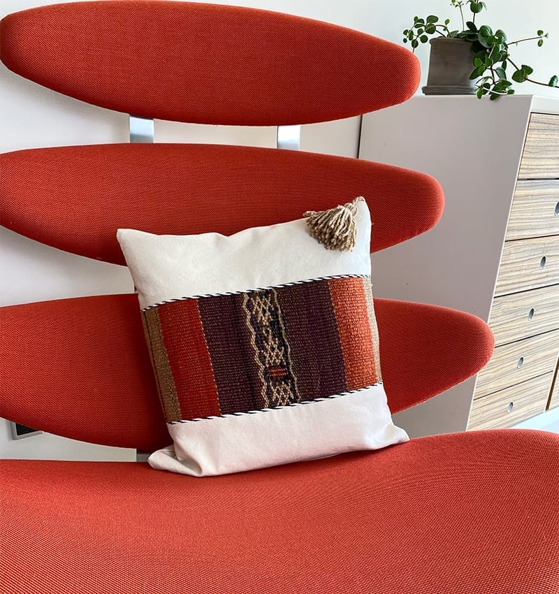 Håndlavet pudebetræk i hvid med marokkansk mønster i røde nuancer oven på en lænestol