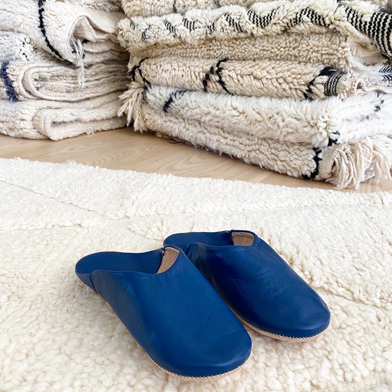 Marokkanske håndlavede slippers i blå oven på beni ouarain tæppe