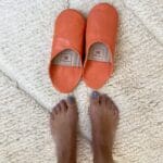 Marokkanske håndlavede slippers i orange med fodmodel ved siden af