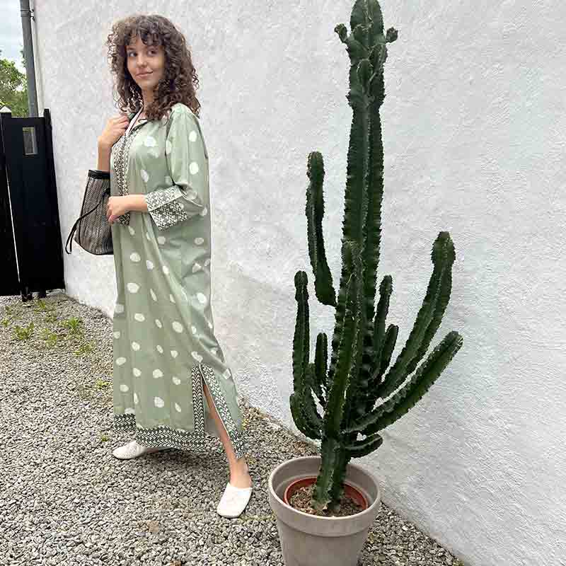 Model i marokkansk håndvævet kjole i lysegrøn med hvide prikker ved siden af kaktus