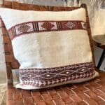 Håndvævet vintage kelim montagne pudebetræk i beige med marokkansk mønster i sort, rød og hvid på loungestol