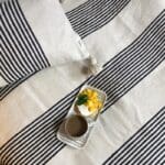Hvidt marokkansk håndvævet sengetæppe med sorte striber og hvide pomponer, med et morgenmadsfad på