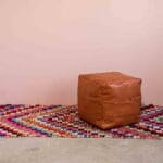 Håndvævet boucherouite tæppe i flerfarvet pile mønster med pink toner, med læderpuf ovenpå