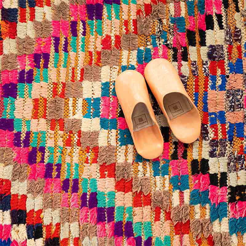 Håndvævet boucherouite tæppe i flerfarvet pile mønster med pink toner, med hjemmesko ovenpå, tæt