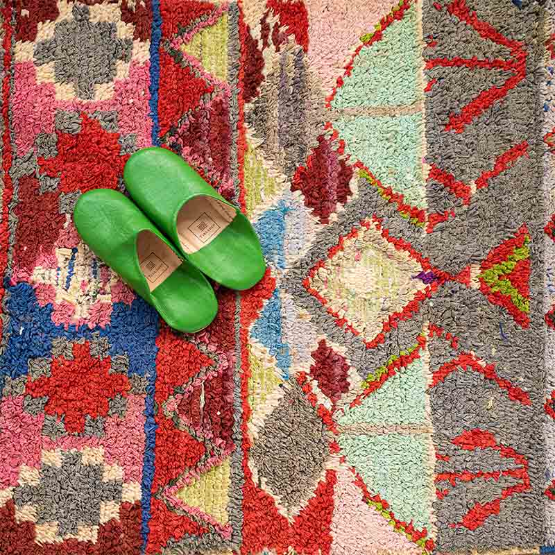 Håndvævet boucherouite tæppe i flerfarvet mønster med røde toner, med hjemmesko ovenpå, tæt
