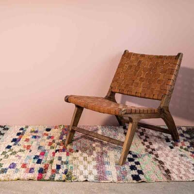 Marokkansk håndvævet Boucherouite tæppe i flerfarvet mønster, med loungestol ovenpå