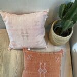 Marockanskt handvävt kuddfodral från kaktussilke i rosa och terrakottafärg med detaljer, bredvid kaktus