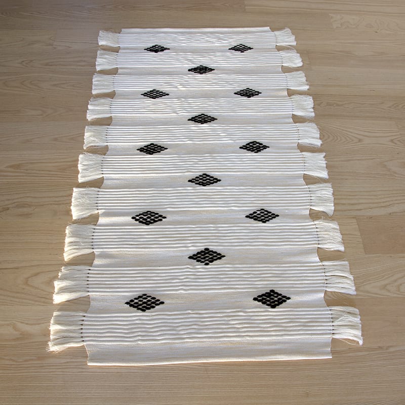 Håndvævet bomuldstæppe i hvid med marokkansk stribemønster og prikmønster i sort med hvide kvaster