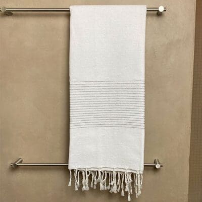 marokkansk håndvævet hammam håndklæde med sølvstriber hængende ude på et badeværelse