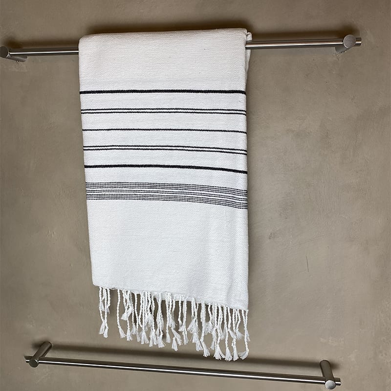 Hivdt marokkansk håndlavet hammam håndklæde med sorte striber, hængende på et badeværelse
