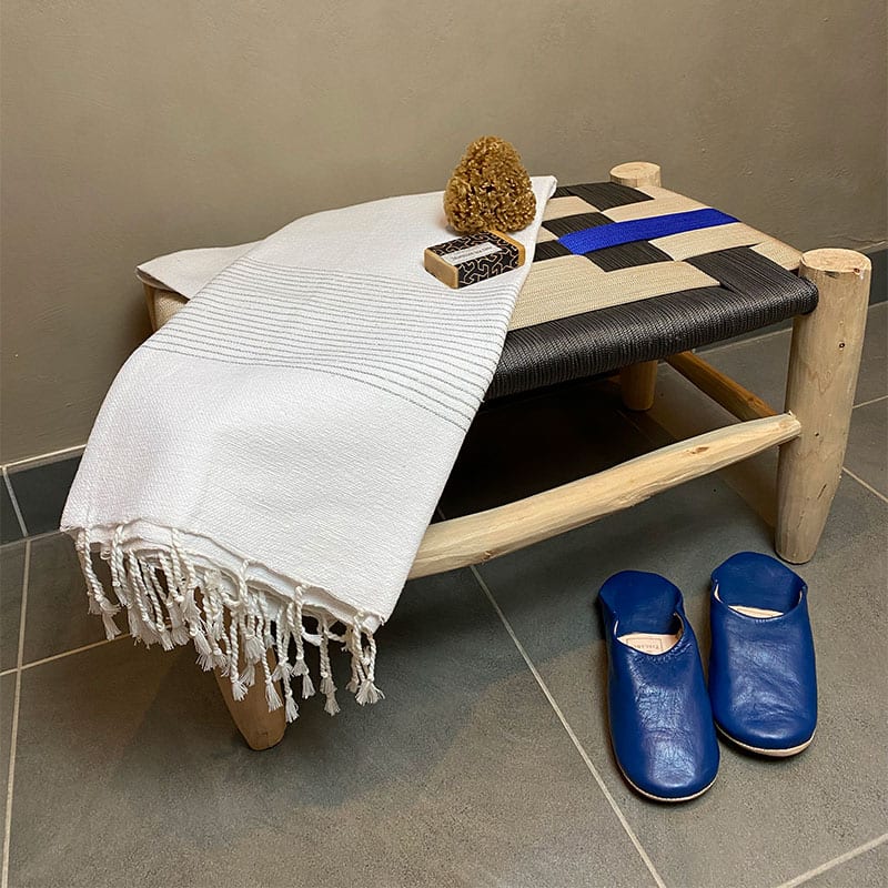 marokkansk håndvævet hammam håndklæde med sølvstriber ude på et badeværelse med dekorationer rundt om