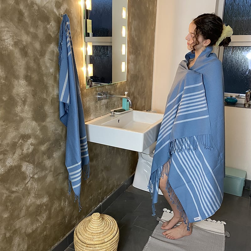 Model iført marokkansk håndvævet hammam håndklæde i blå ude på et badeværelse