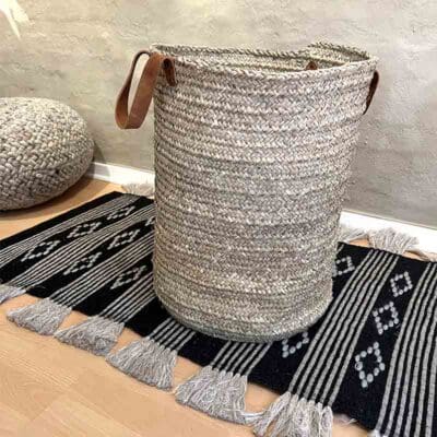 Moroccan handwoven basket with leather handle standing in family room