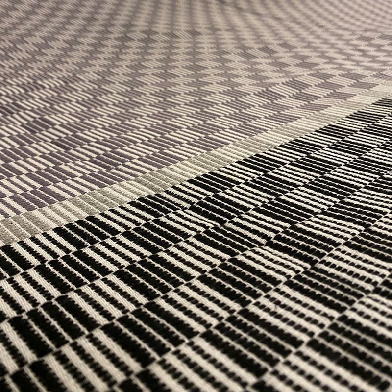 Marokkansk håndvævet sengetæppe med hvidt og sort firkantet mønster, tæt