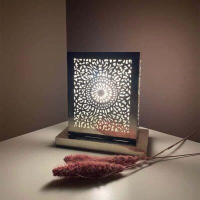Håndlavet firkantet bordlampe med marokkansk mønster, tændt i mørket med blomster ved siden af