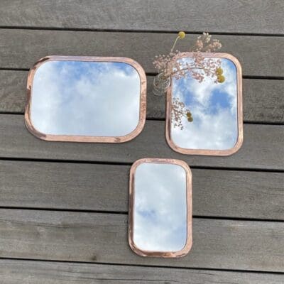 Three rectangular Moroccan handmade mirrors with rounded edges in rose gold metal in various variations, with floral decorations around