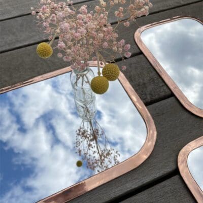 Three rectangular Moroccan handmade mirrors with rounded edges of rose gold metal in different varieties, with floral decorations around, close