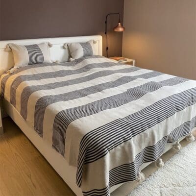 Hvidt marokkansk håndvævet sengetæppe med sorte striber og hvide pomponer