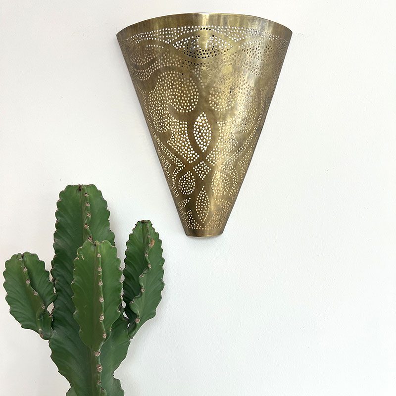 Håndlavet væglampe i guldmetal med marokkansk mønster, hængende ved siden af kaktus