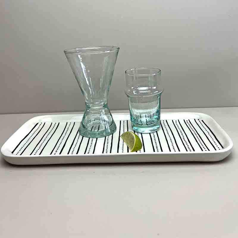 Håndlavede transparente bledi glas og vinglas stående ovenpå på et fad, med en lime foran