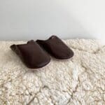 Marokkanske håndlavede slippers i mørkebrun oven på beni ouarain tæppe