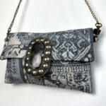 Håndtaske i grålige nuancer med kobber kæde og stor dekorativ knap