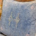 Zarter blauer Kissenbezug aus Kaktusseide mit gelben und rosa Ziernähten.