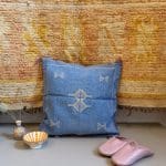 Blauer Kissenbezug aus Kaktusseide mit gelben und rosa Ziernähten.