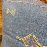 Blauer Kissenbezug aus Kaktusseide mit gelben und rosa Ziernähten.