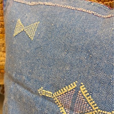 Blauwe kussensloop van cactuszijde met gele en roze stiksels.