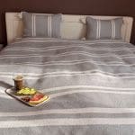 Smukt bomuldssengetæppe håndlavet i Marokko. Grå- og hvidstribet med pompommer i hvert hjørne.