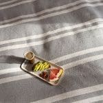 Smukt bomuldssengetæppe håndlavet i Marokko. Grå- og hvidstribet med pompommer i hvert hjørne.