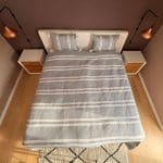 Smukt bomuldssengetæppe håndlavet i Marokko. Grå- og hvidstribet med pompommer i hvert hjørne.