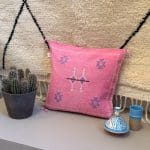 Kussensloop van cactuszijde, handgemaakt in Marokko. Roze met blauwe en witte stiksels.
