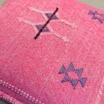 Kussensloop van cactuszijde, handgemaakt in Marokko. Roze met blauwe en witte stiksels.