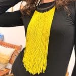 Perlekjede med gule perler og svart kjede flettet i lær.