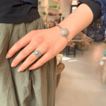 Tilelli is een eenvoudige en prachtige ring waarvan het zilveren patroon op een bloem lijkt, met een parel in het midden als middelpunt.