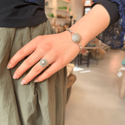 Tilelli er en enkel og vakker ring med et sølvmønster som ligner en blomst med en perle i midten som midtpunkt.