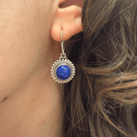 Boucle d'oreille pendante en argent, ornée d'une pierre ronde bleu marine entourée de points.