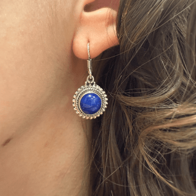 Boucle d'oreille pendante en argent, ornée d'une pierre ronde bleu marine entourée de points.