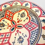Rød keramik tallerken med grønne prikker og gule detaljer håndlavet i marokko, måler 26 cm.