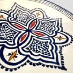 Assiette en céramique bleue ornée de motifs et de détails rouges et jaunes, fabriquée à la main au Maroc. Dimensions : 26 cm.