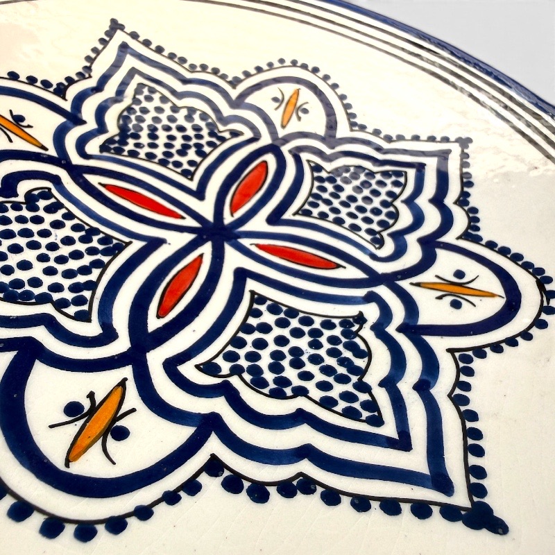 Assiette en céramique bleue ornée de motifs et de détails rouges et jaunes, fabriquée à la main au Maroc. Dimensions : 26 cm.