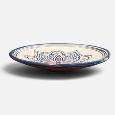 Assiette en céramique bleue ornée de motifs et de détails rouges et jaunes, fabriquée à la main au Maroc. Dimensions : 26 cm.