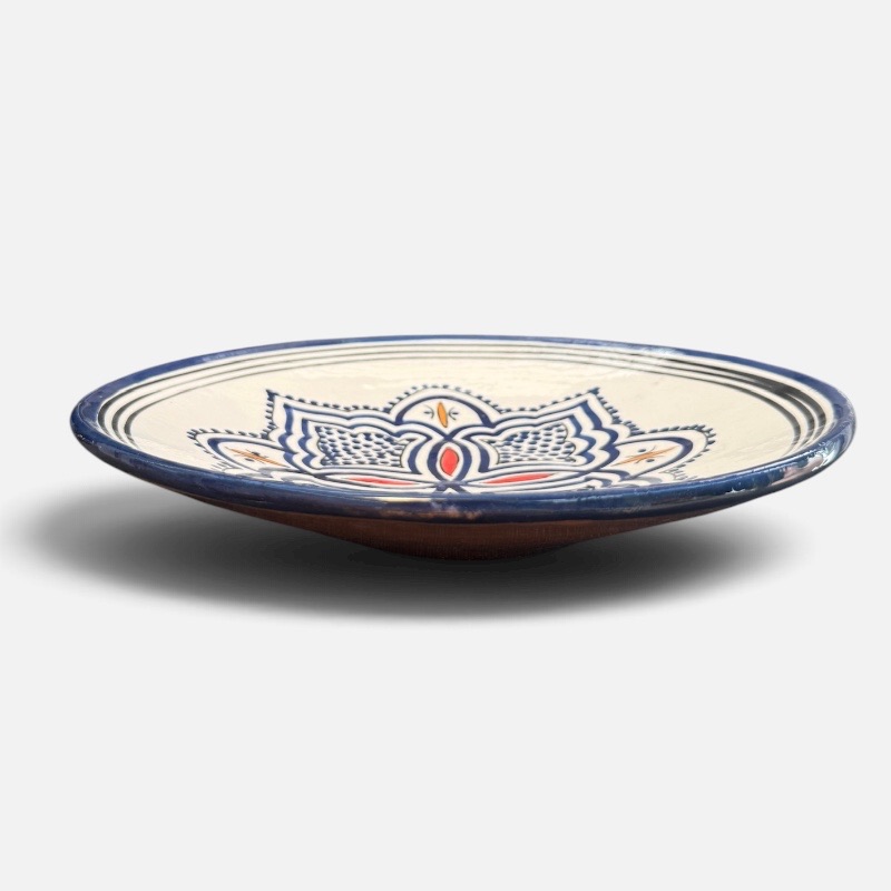 Assiette en céramique bleue ornée de motifs et de détails rouges et jaunes, fabriquée à la main au Maroc. Dimensions : 26 cm.
