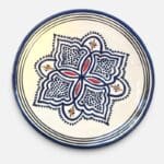 Assiette en céramique bleue ornée de motifs et de détails rouges et jaunes, fabriquée à la main au Maroc. Dimensions : 26 cm.